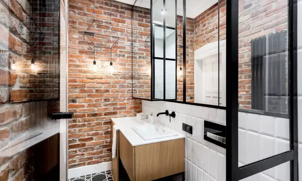 Łazienka w stylu industrialnym, loft z ceglanymi ścianami, drewnianą szafką i czarnymi akcentami.