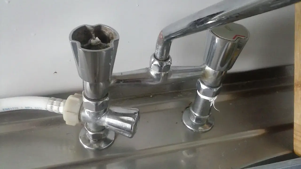 Zepsuty kran, jak odkrecic kran? Widoczne są dwa pokrętła, jedno z osadem.