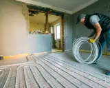 Instalator układa rury do ogrzewania podłogowego w bloku. To może być nielegalne ogrzewanie podłogowe, jeśli nie ma zgody.