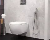 Nowoczesna łazienka z podwieszaną miską WC i bidetta na jakiej wysokości zamontowana, obok uchwyt na papier toaletowy.