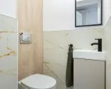 Nowoczesna łazienka z toaletą i umywalką. Widoczny przycisk do spłuczki, który może być pomocny, gdy zastanawiasz się, jak naprawić spłuczkę.