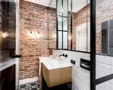 Łazienka w stylu industrialnym, loft z ceglanymi ścianami, drewnianą szafką i czarnymi akcentami.
