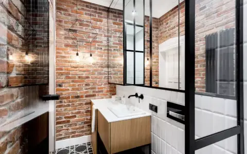 Łazienka w stylu industrialnym, loft z ceglanymi ścianami, drewnianą szafką i czarnymi akcentami.