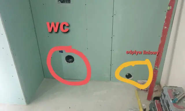 Oznaczone otwory w ścianie z płyt gipsowo-kartonowych: czerwone dla WC, żółte dla odpływu liniowego.