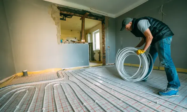 Instalator układa rury do ogrzewania podłogowego w bloku. To może być nielegalne ogrzewanie podłogowe, jeśli nie ma zgody.